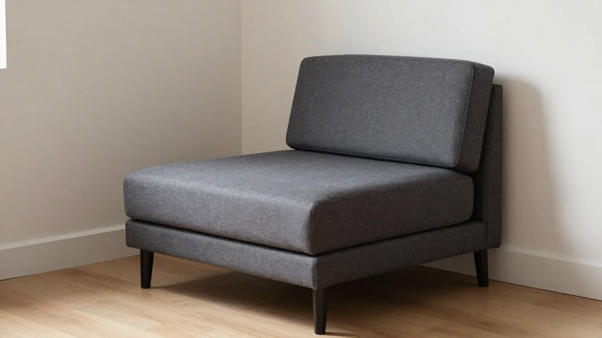 Canapé convertible 1 place en tissu gris anthracite posé contre le mur d'une petite pièce